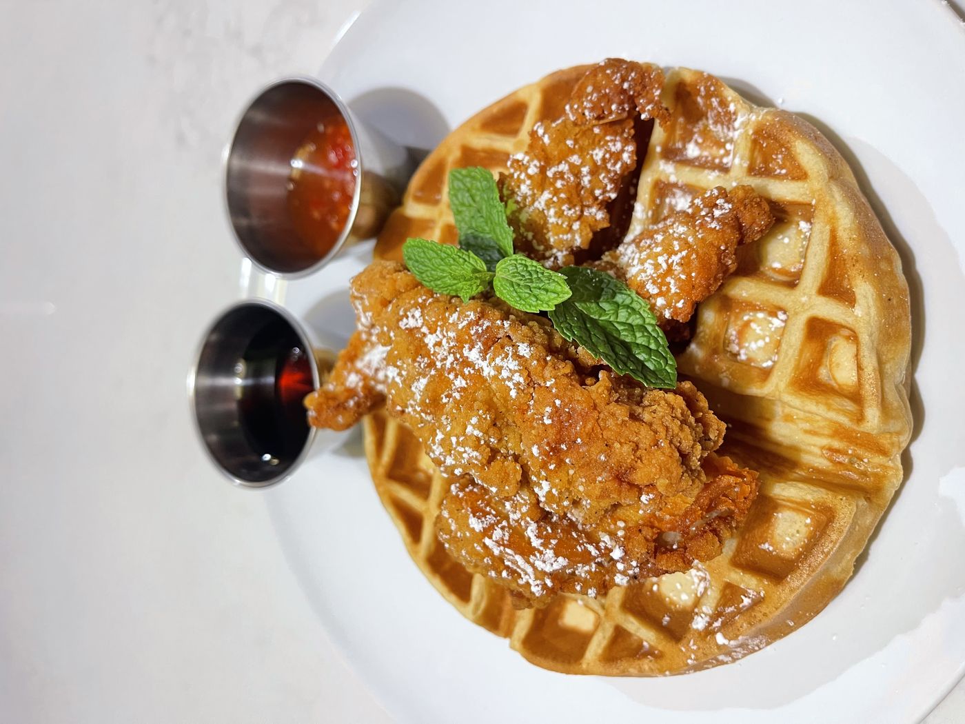 Fried chicken on a waffle with syrup and chili sauce