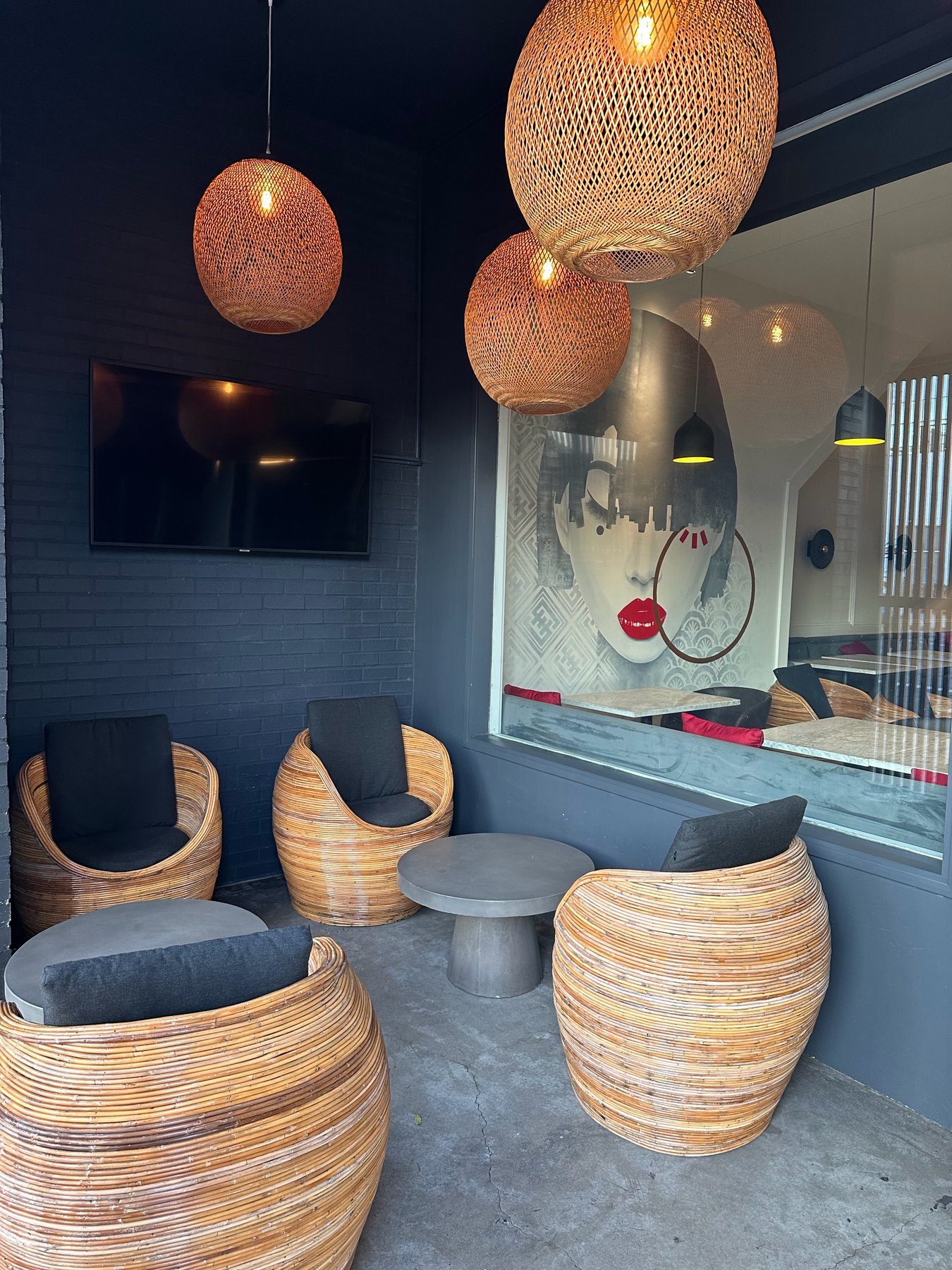 Patio seating with rattan chairs, woven pendant lights, and the dining-room mural through the glass