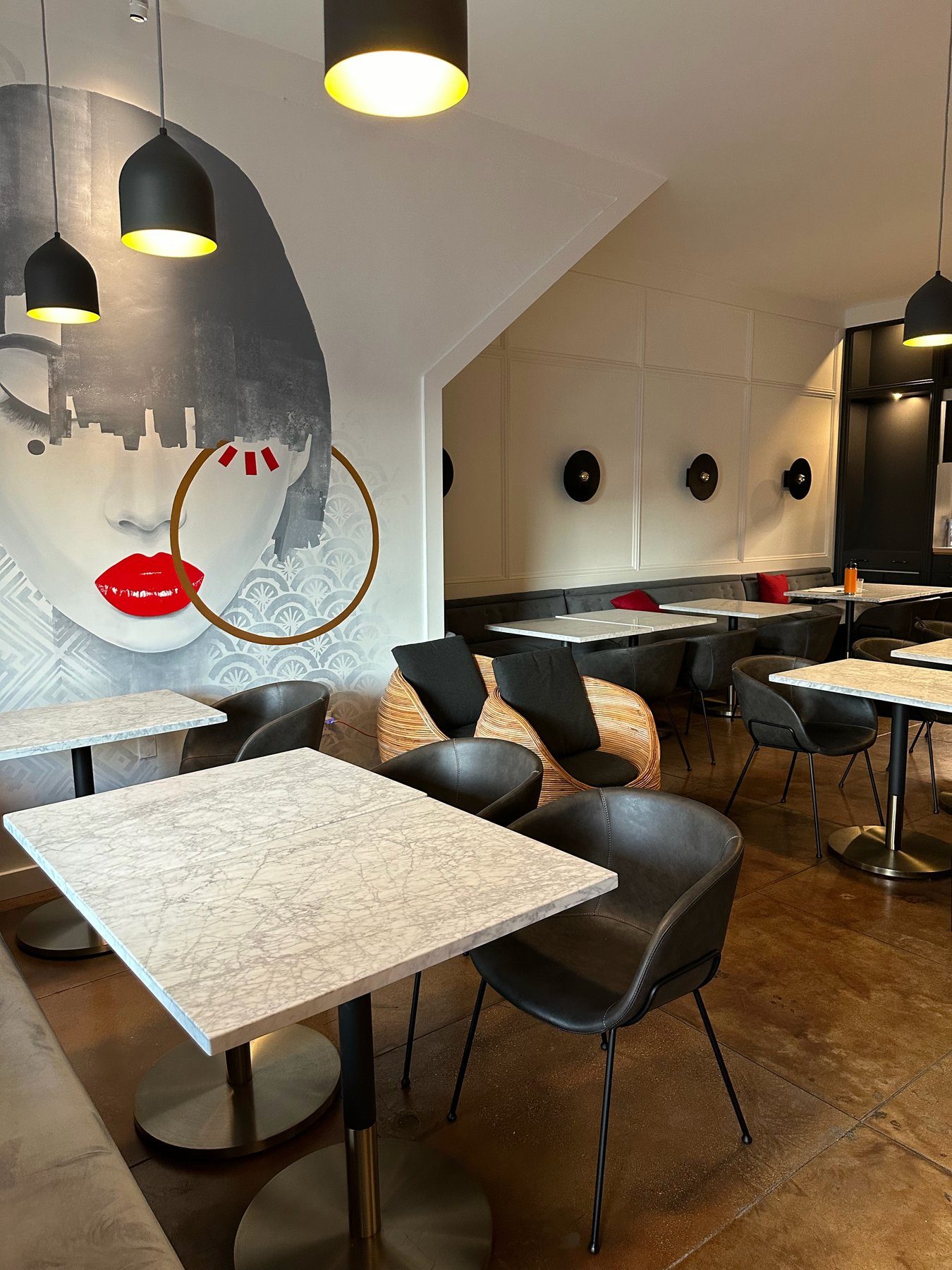 Dining room at Spelling Thai Bistro, with the mural, marble tables, and black chairs