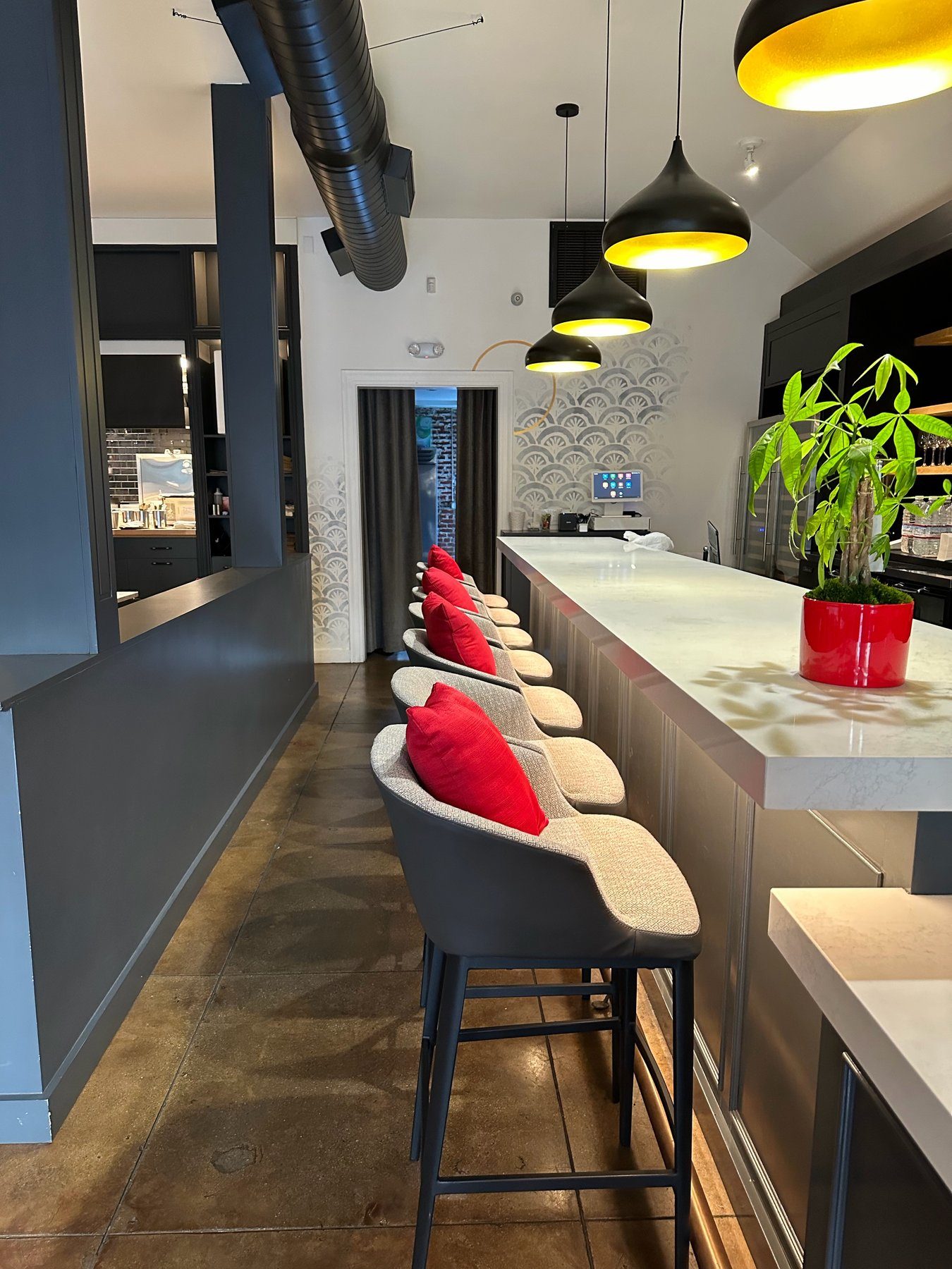 Bar at Spelling Thai Bistro with grey stools, red cushions, and brass-lined pendants